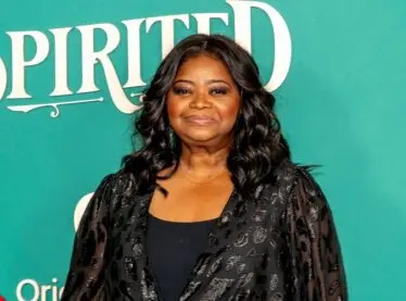 Octavia Spencer at a red carpet premiere in a black dress looking happy and smiling.
