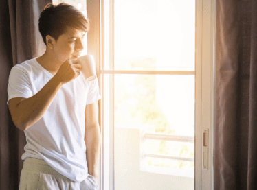 Actor enjoying a cup of coffee after waking up feeling refreshed because he has good nighttime habits