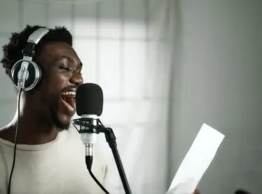 African American voice actor recording his lines in a studio.