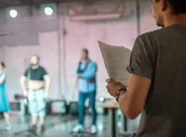 A casting director walking into a room of actors rehearsing.