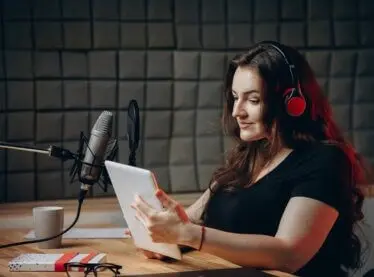 A female voice actor reading a script on a table from her home studio.