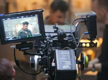 Camera view of a movie being filmed, actor in frame for a dramatic scene.