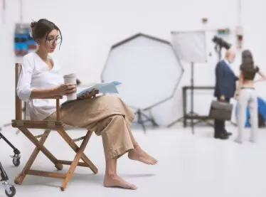 An actress on set reading over her lines while having a cup of coffee.