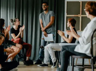 Diverse group of actors applauding a peer at a workshop.
