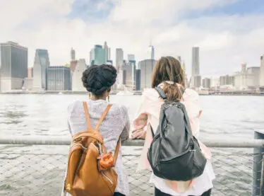 Two friends overlooking New York City from the Brooklyn Bridge.