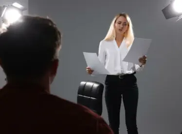 Female actor holding several scripts auditioning for a casting director.
