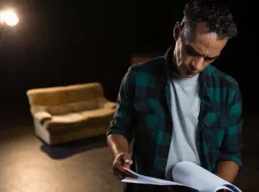 Actor reading his lines on stage at rehearsal for a living room scene.