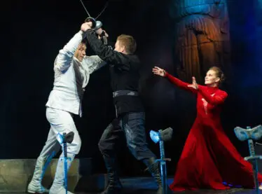 Shakespeare actors performing a sword fight scene in a play.