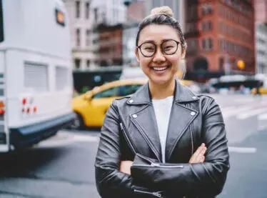 Smiling Asian woman in a leather jacket outside.