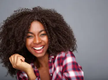 Happy African woman in a red and white flannel shirt smiling.