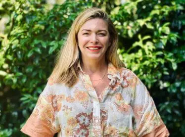 Casting director Natalie Jane Harvie smiling outside in a lush garden.