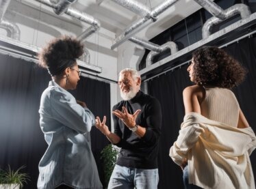 A bearded acting teacher training two of his students.