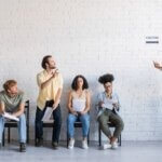 A bearded casting director calling over an actor from the bench.
