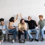 A diverse group of actors waiting to audition. Two are high-fiveing.