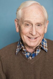 Actor Michael Canetty smiling in a sweater vest.