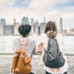 Two friends overlooking New York City from the Brooklyn Bridge.