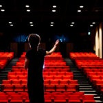 Young woman rehearsing her song in an empty auditorium.