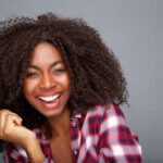 Happy African woman in a red and white flannel shirt smiling.