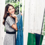 Happy asian woman admiring her new denim dress in the mirror.