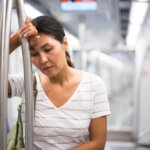 Sad Asian woman on the subway train looking defeated and burnt out.