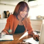 An actress on her laptop with a notepad researching ways to spruce up her casting profile.