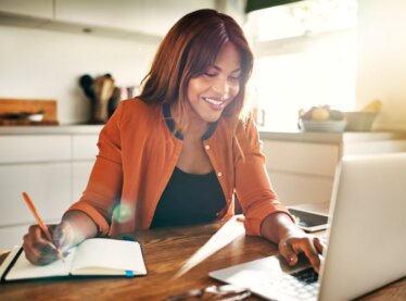 An actress on her laptop with a notepad researching ways to spruce up her casting profile.