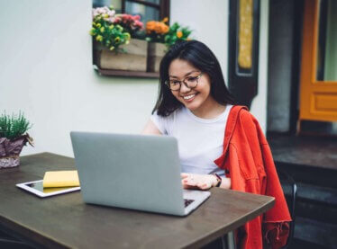 An Asian actress at home on her laptop researching self submitting for roles.