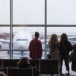 Actors waiting on the runway at an airport in winter staring at a stationed plane.