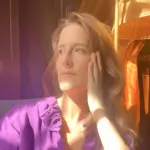 Jennifer Venditti in a purple shirt inside with the sun shining.