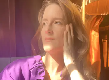 Jennifer Venditti in a purple shirt inside with the sun shining.