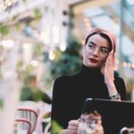 An actress known for her facial expressions on her laptop outside with a perplexed expression.