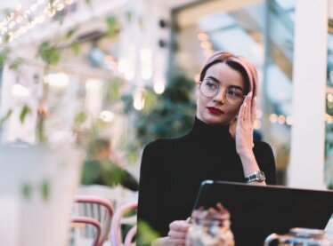 An actress known for her facial expressions on her laptop outside with a perplexed expression.